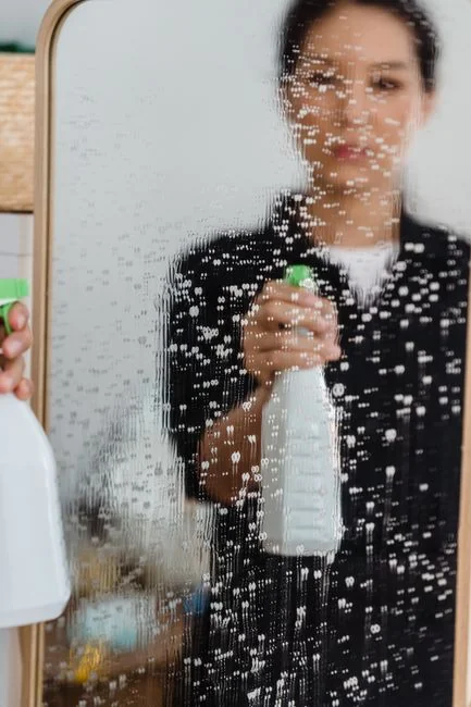 A professional cleaner in protective gear vacuuming the floor in a modern living room.
